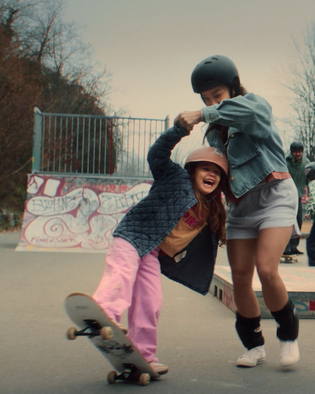 Frau mit Kind am Skateboarden.