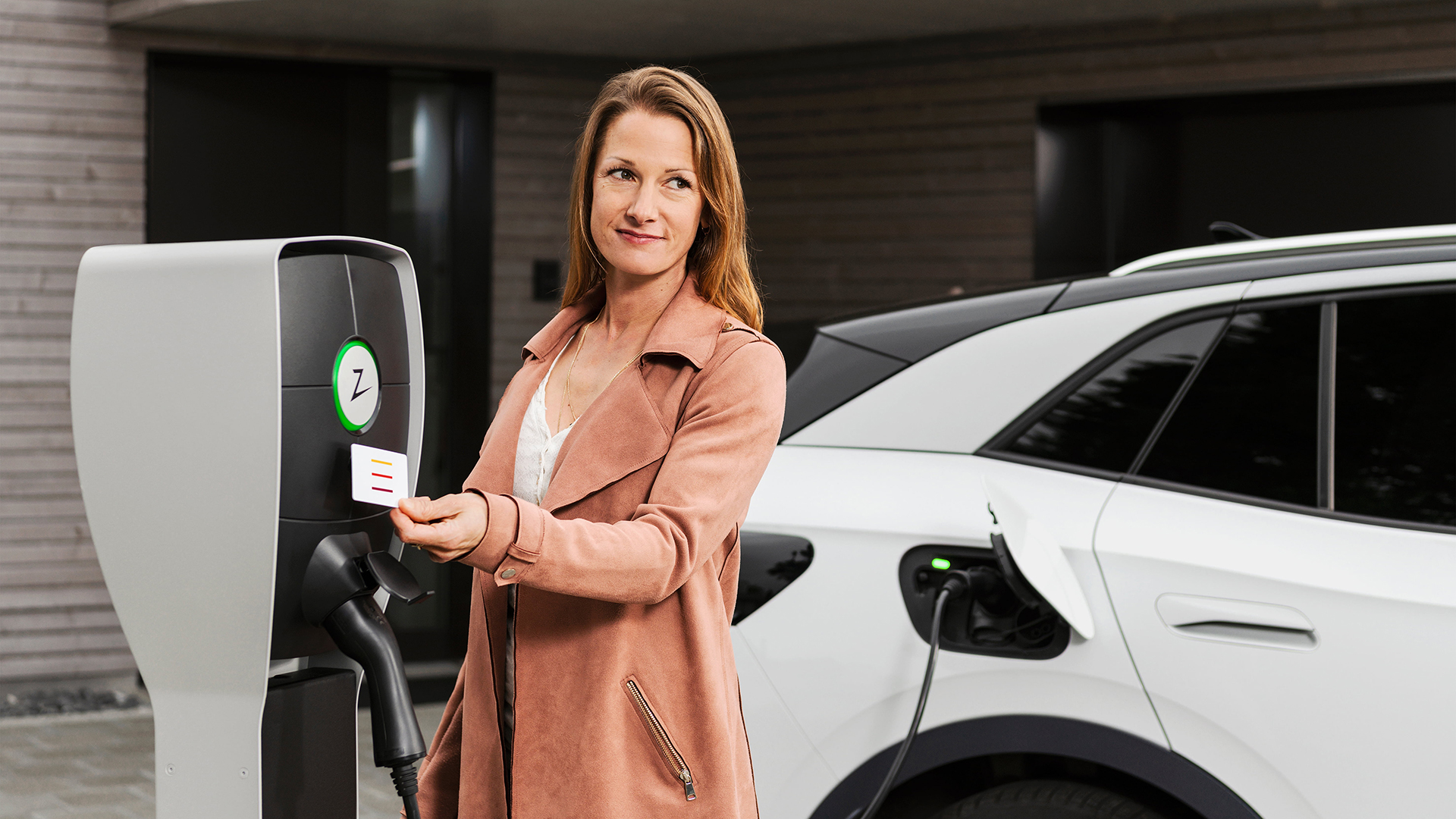 Frau lädt ein Elektroauto an einer E-Ladestation von IB-Murten vor einem Wohnhaus