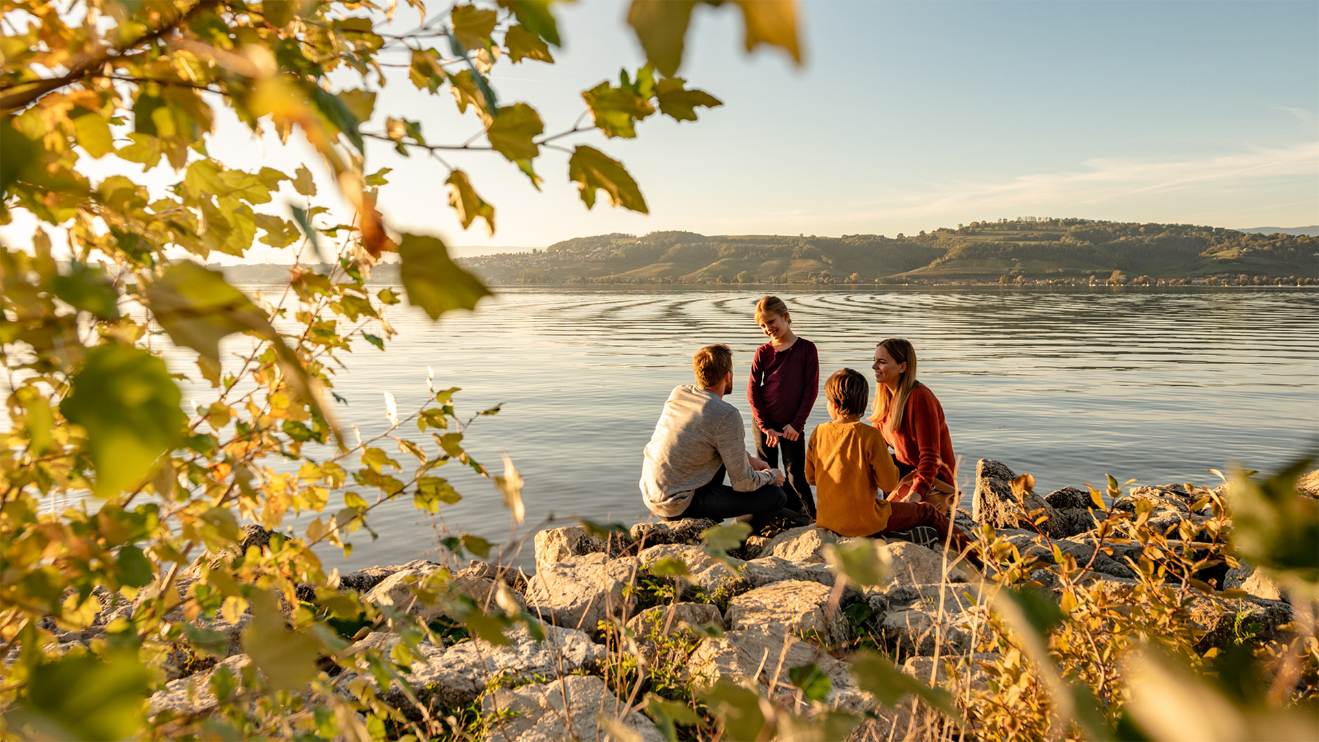 Familie sitzt am Seeufer bei Murten und geniesst die Natur in der Region von IB-Murten