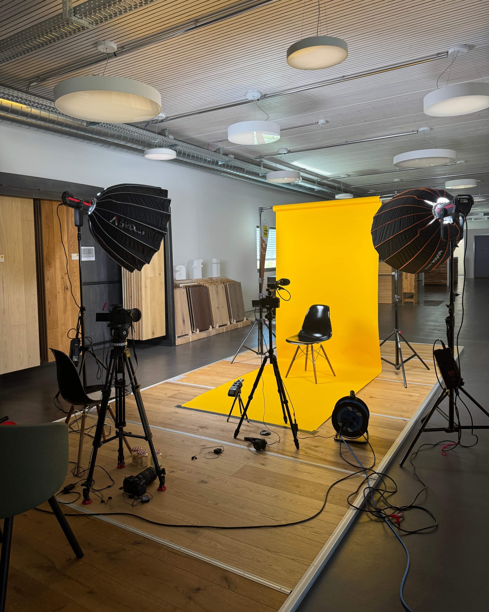 Filmset für den Jubiläumsfilm von OLWO mit gelbem Hintergrund, Kameras und Studiobeleuchtung.